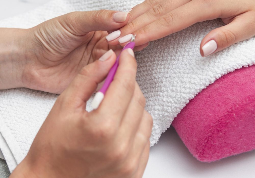 Close-up of beautician painting a woman's nails with a brush in a nail salon. Costumer receiving a manicure.